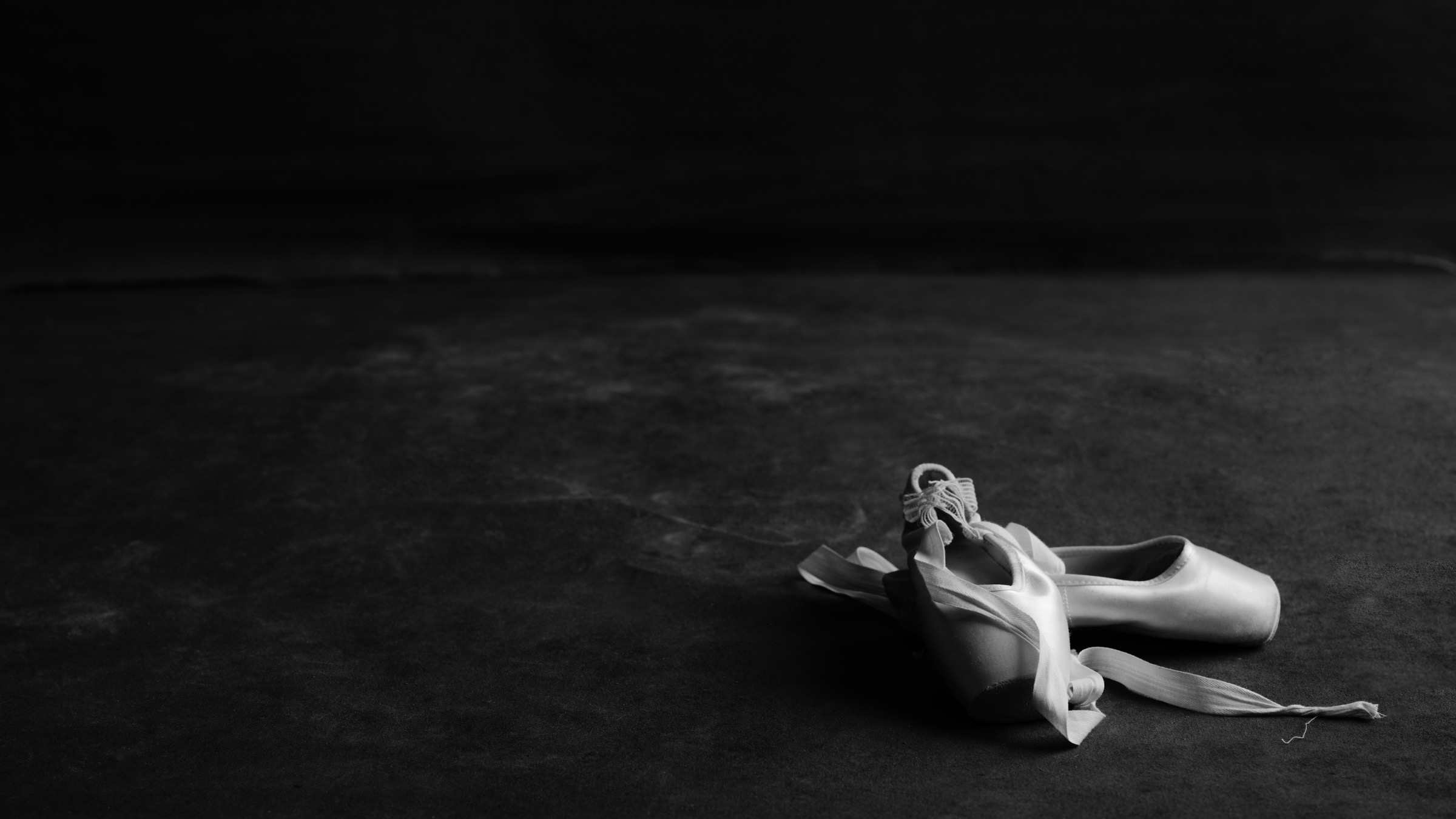 Ballet pointe shoes resting on studio floor — black and white